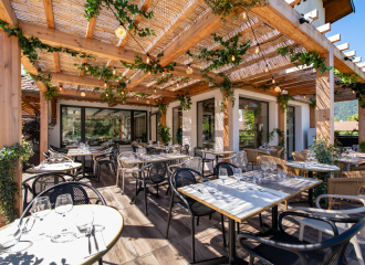 terrasse avec tables dressées sous pergolas en bois et végétaux