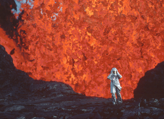Katia Krafft, vêtue d'une combinaison aluminisée, se tient près d'une éruption de lave au volcan Krafla, en Islande